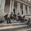Students sit on the steps of a classical building in Rome.